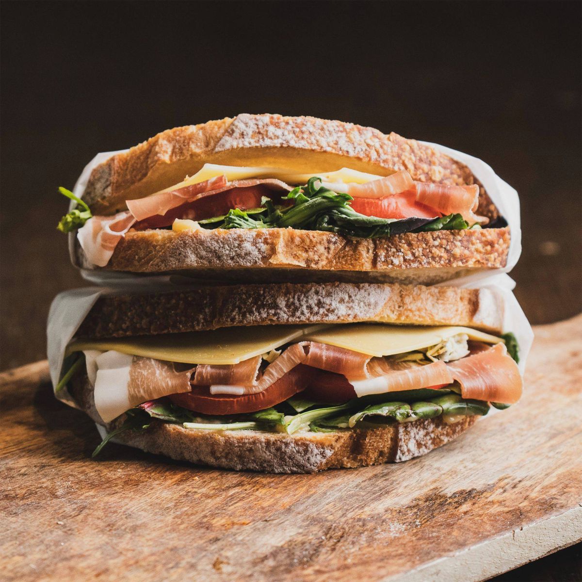 Sandwichs au jambon, fromage et salade sur une planche en bois